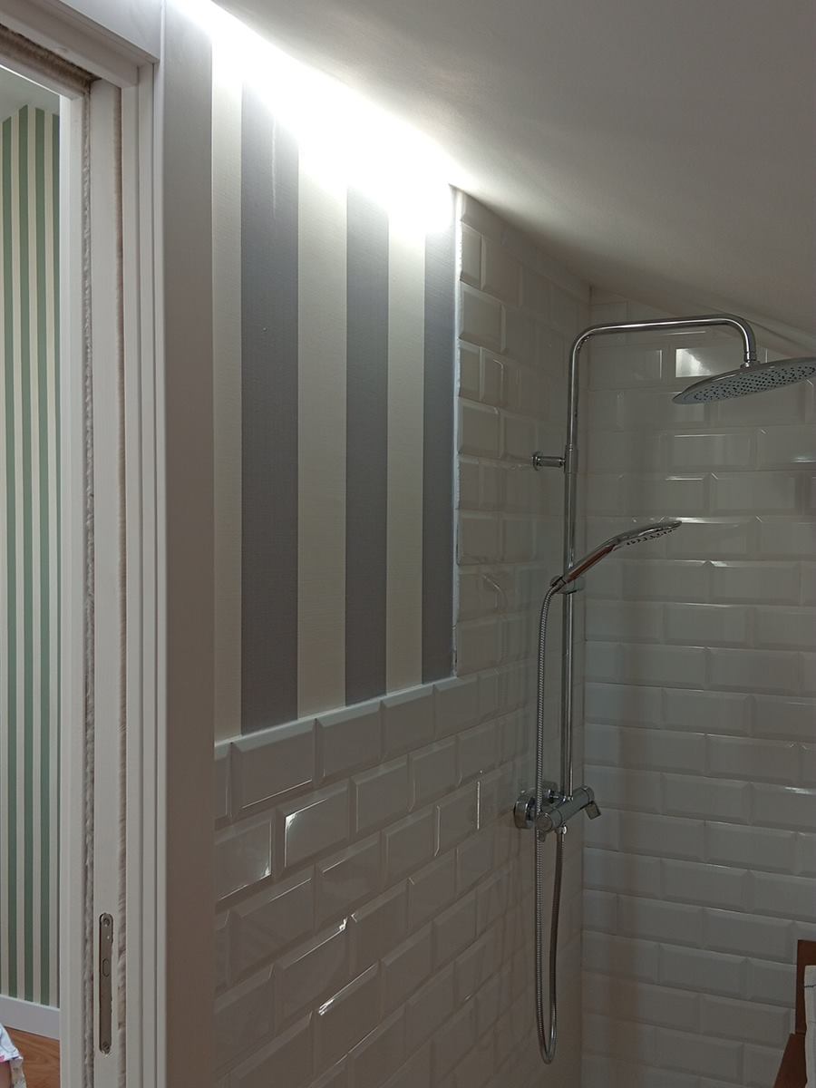 Baño con ducha y pared a rayas grises y blancas por encima del azulejo