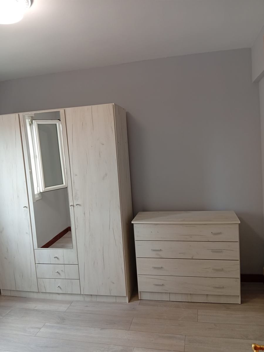 Dormitorio con paredes grises, armario y cómoda claros