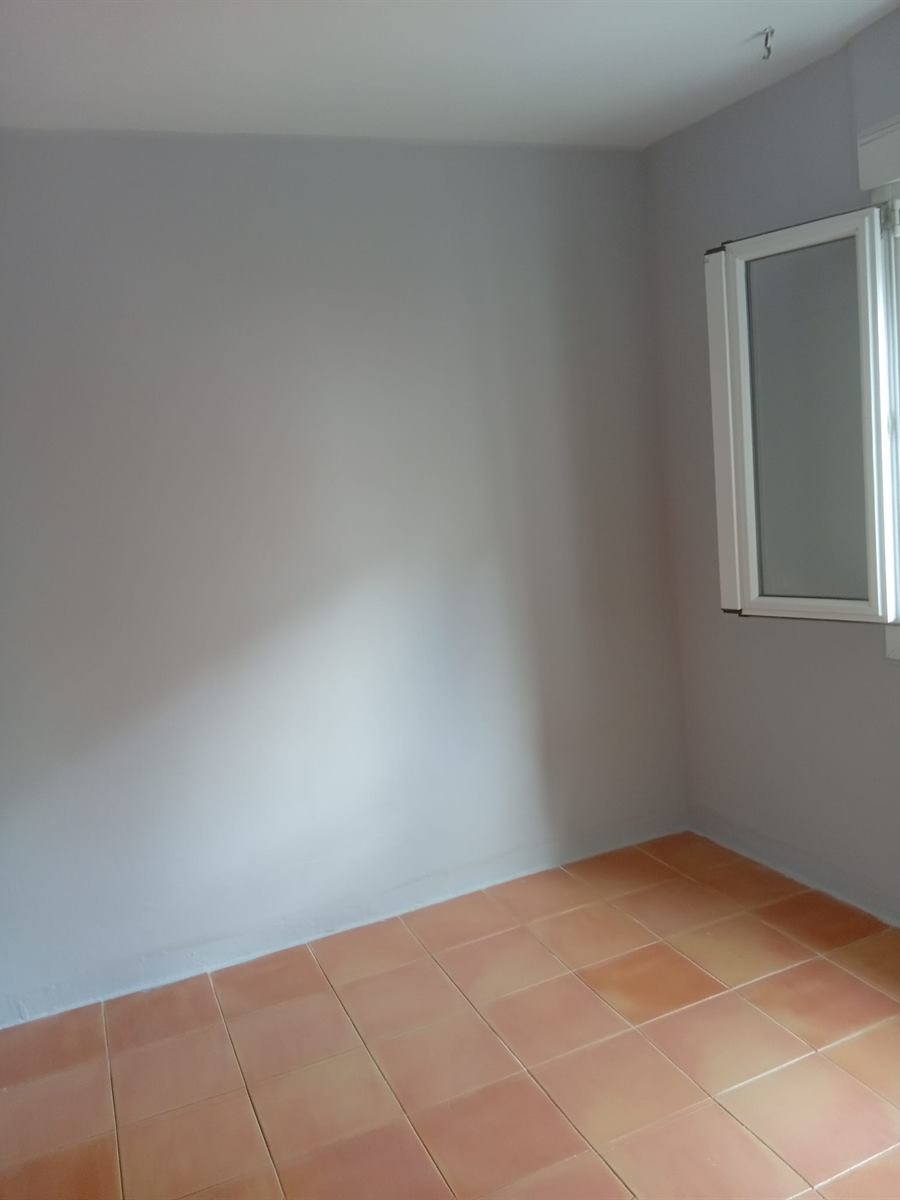 Dormitorio vacío con paredes pintadas en gris perla y suelo de baldosa