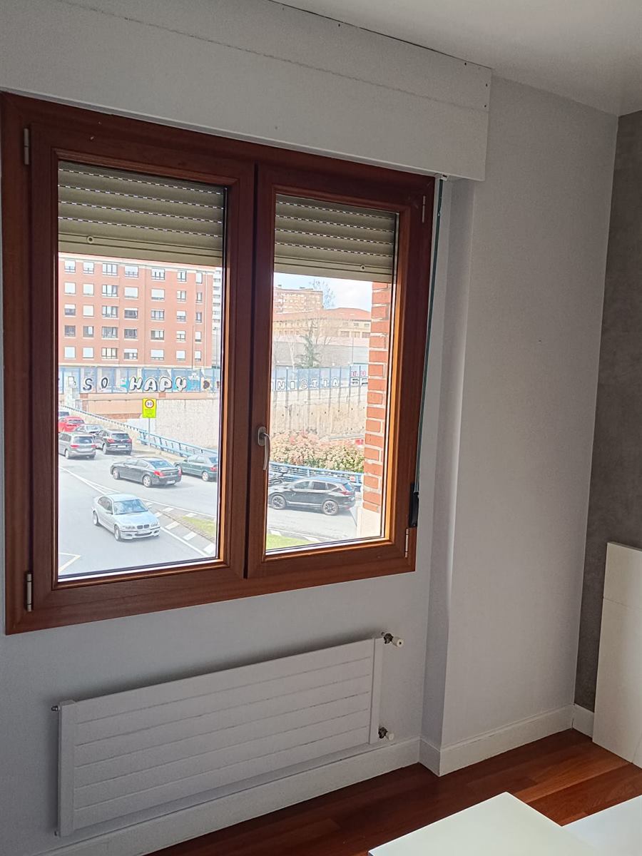 Dormitorio pintado en blanco y gris con ventana de madera
