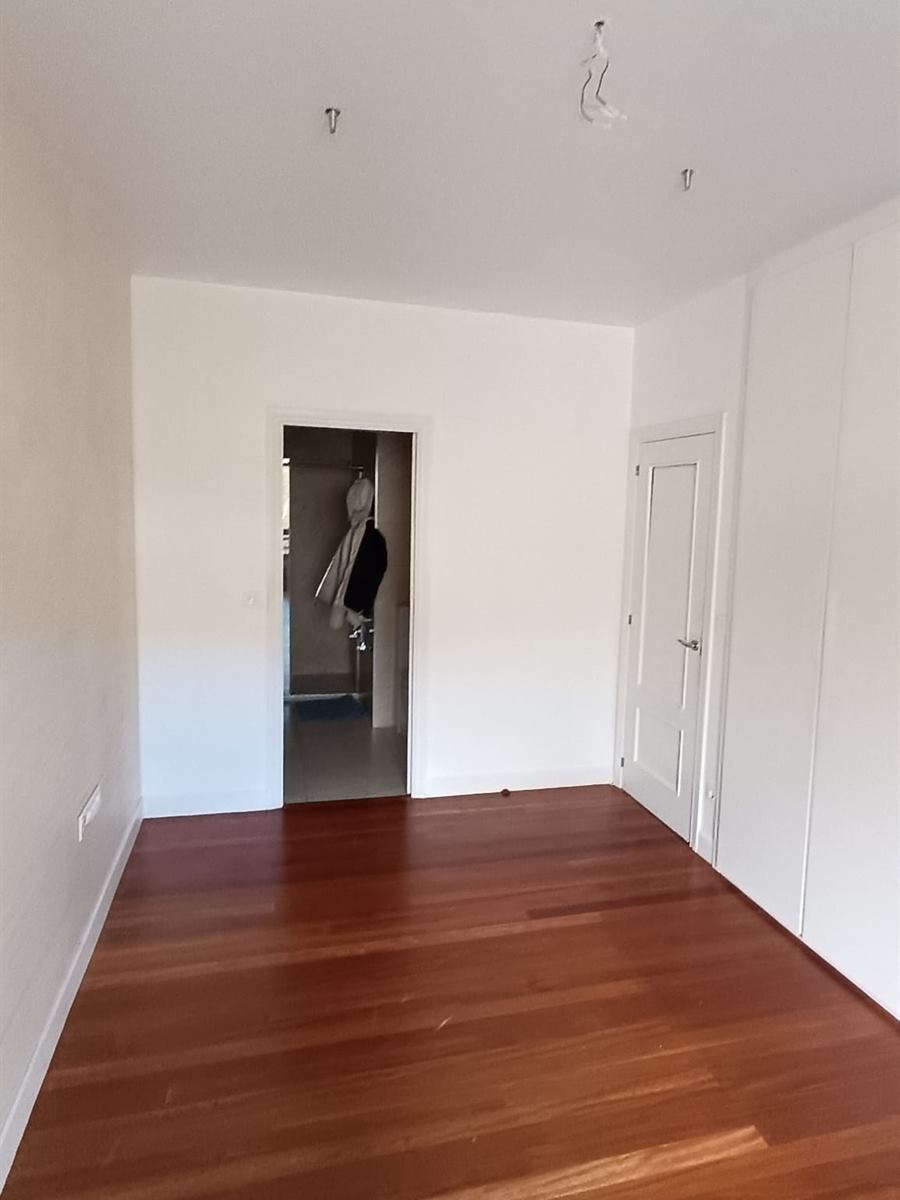 Estancia amplia con paredes y techo pintados en blanco y suelo de parquet